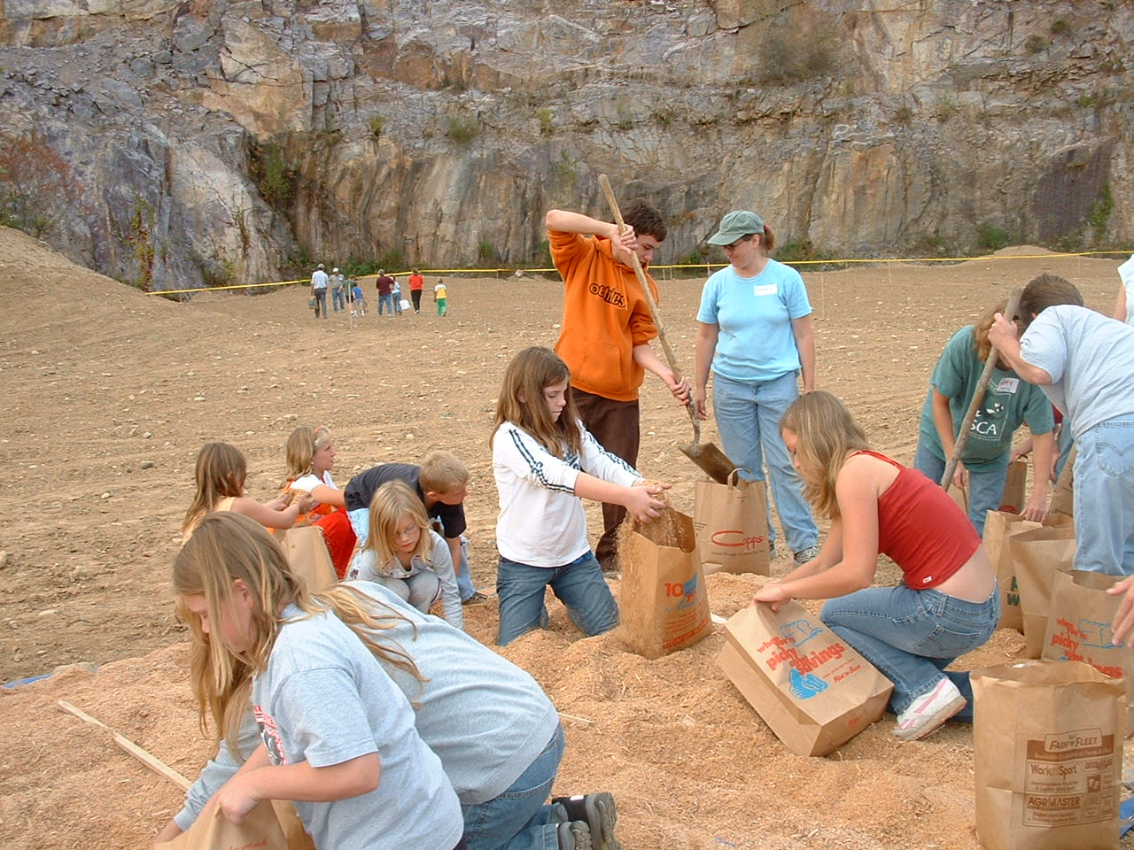  A group of students and adult volunteers mix and bag prairie seeds for planting.