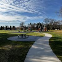 Photo of walking path to the playground through grass, underneath a blue sky