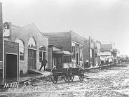 Plain: Main Street in early 1920's. L-R: Blacksmith Shop, Liegel Garage, Village Hall, Dr. P.H. Fowler's office, Post Office & I