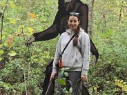 Large Sasquatch cutout in forest with woman and dog posing in front