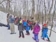 Group of kids and adults learning about snowshoeing