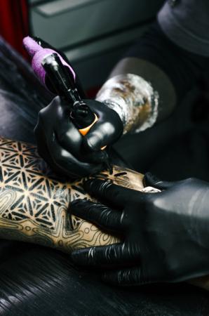 Selective focus photography of tatttoo artist drawing a tattoo