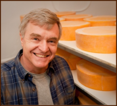 Man next to cheese wheels
