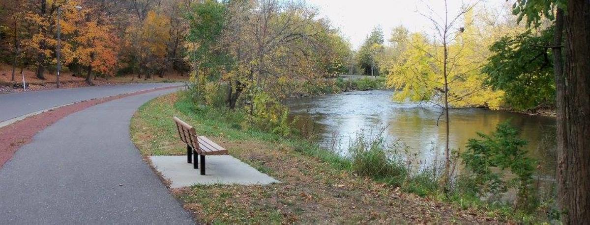 Bench on Baraboo Riverwalk Trail with rapids on Baraboo River in background