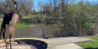A metal sculpture of a crane faces a river to promote a Great Sauk State Trail update