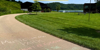 Music in the Park tonight, with Janna and The Junkyard Dawgs, written in chalk on a park path