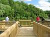 Four people stand on pier at the North End Boat Landing on Lake Redstone and look over the water while fishing